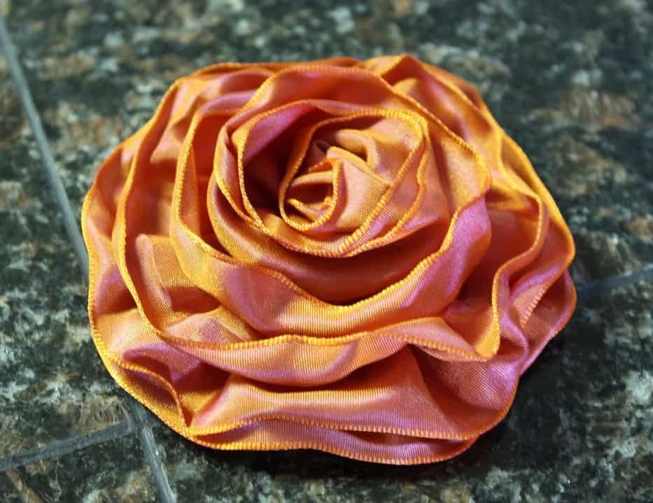 Iridescent orange ruffled ribbon flower.