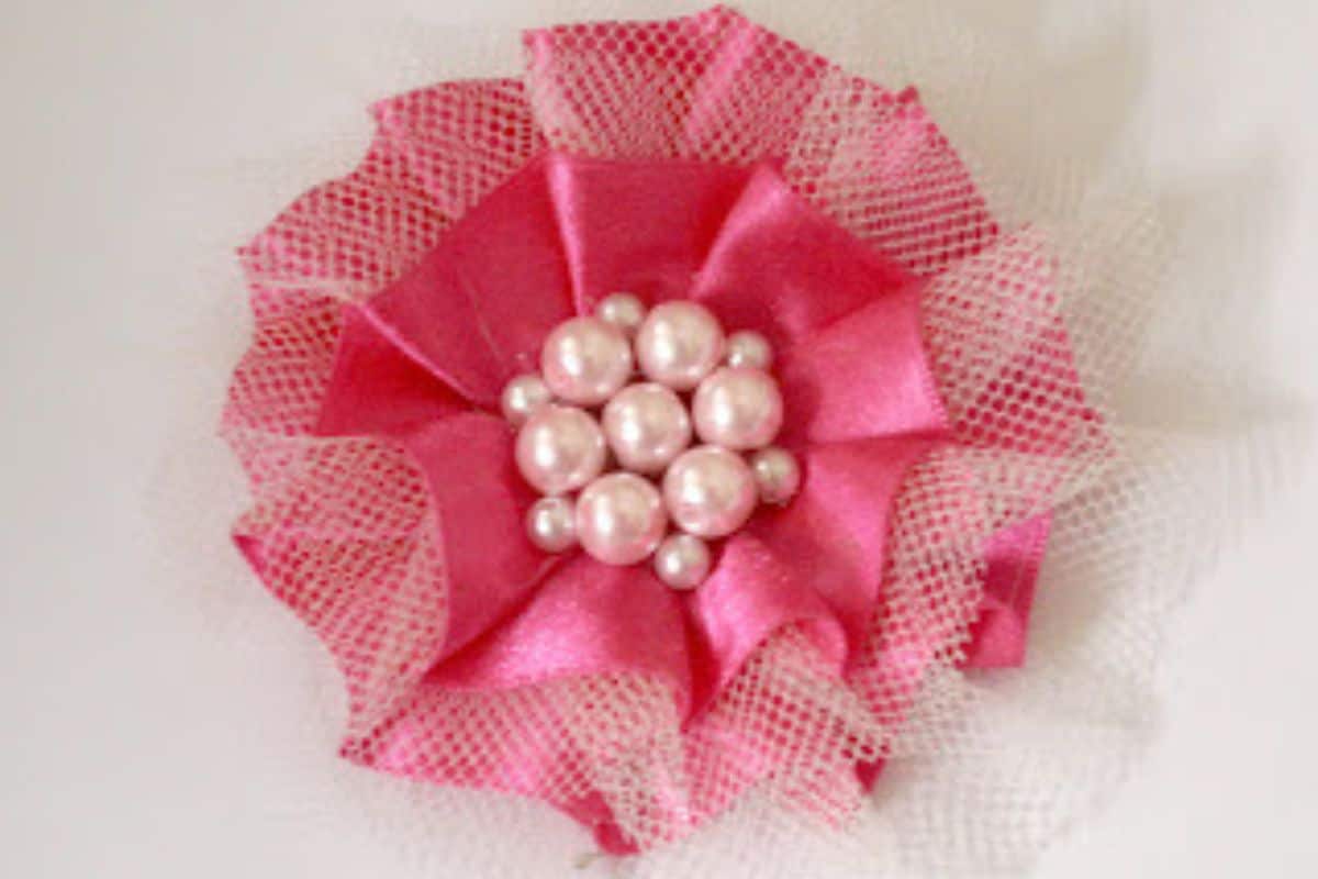Pink sating and tulle flower with pearl beads in the center.