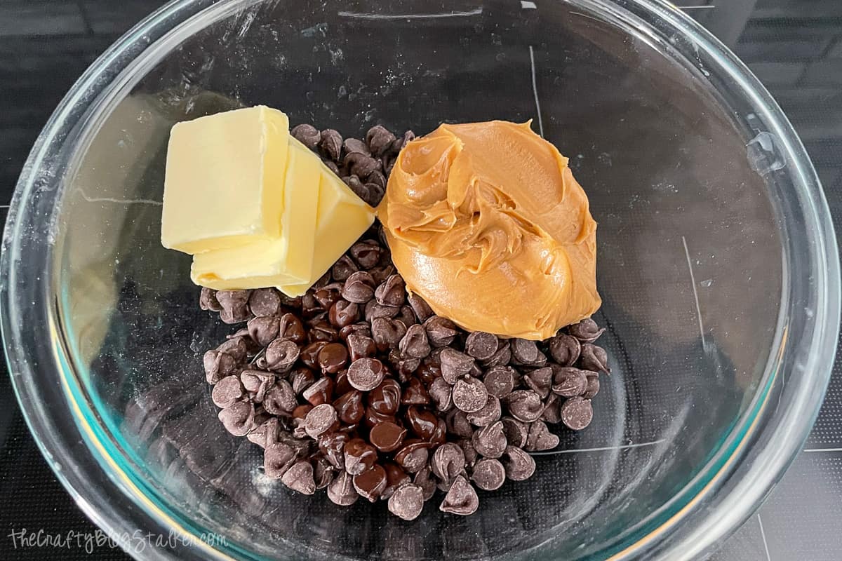 Peanut butter, butter, and chocolate chips in a glass bowl.