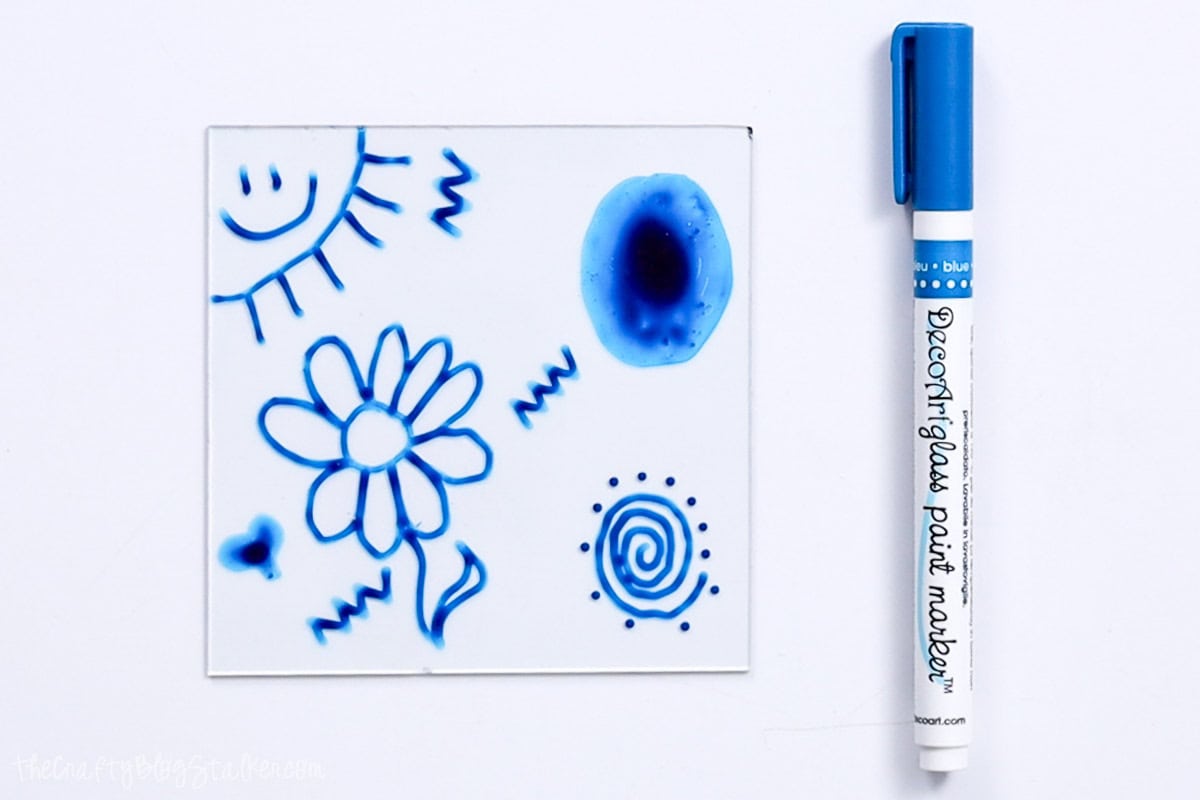 A Deco Art blue glass paint marker next to a glass pane painted with the same paint.