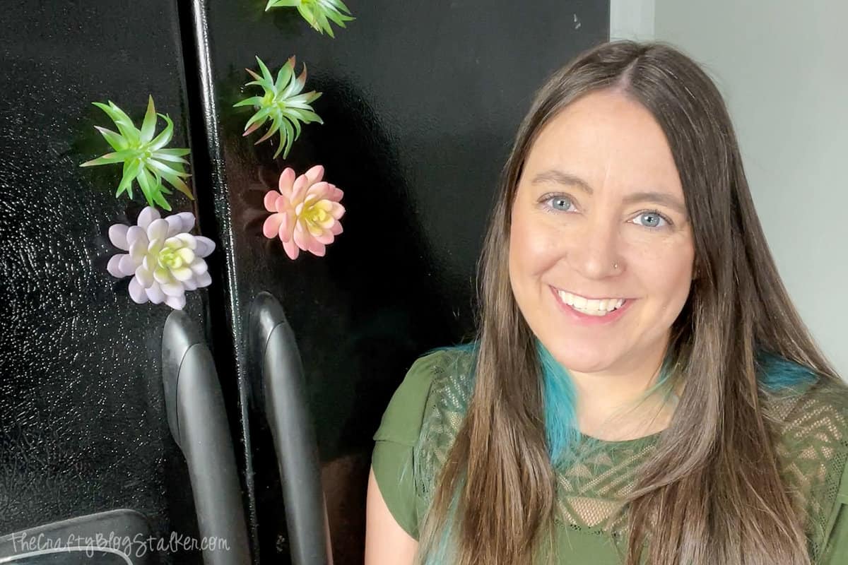 a woman standing by a black fridge with succulent magnets 