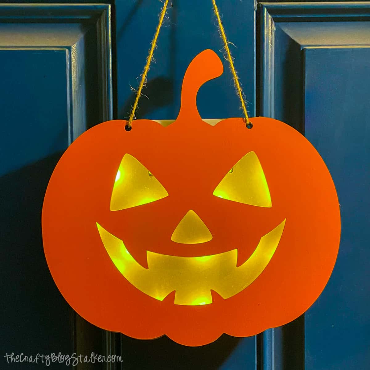 Light up pumpkin hanging on a blue door