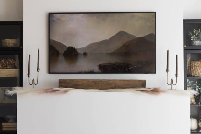 Frame TV above fireplace with Fall Image.