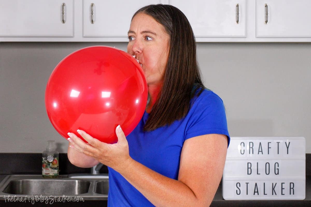 a woman blowing up a red balloon