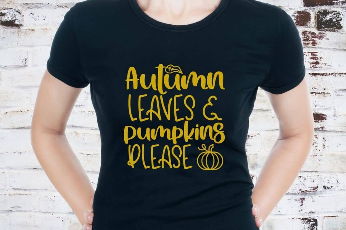 Black shirt with a yellow design that reads, Autumn Leaves and Pumpkin Please.