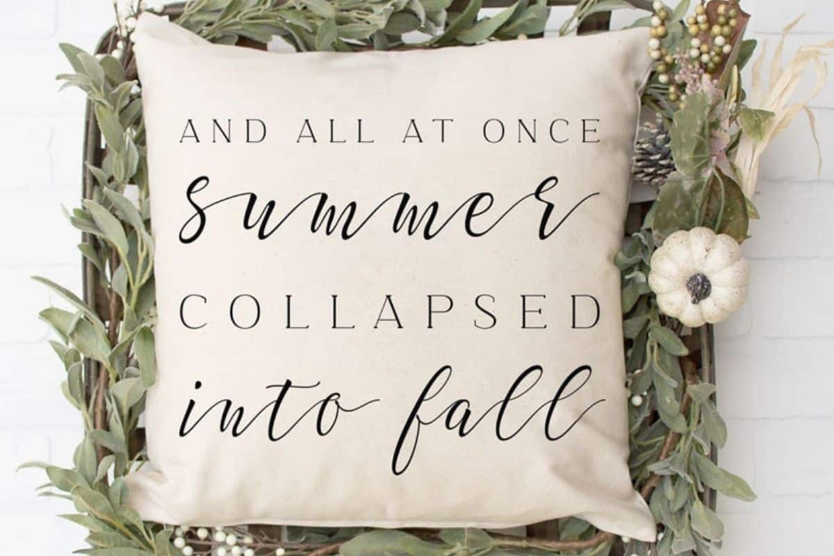 A throw pillow with a design that reads 'And All At Once Summer Collapsed Into Fall'.