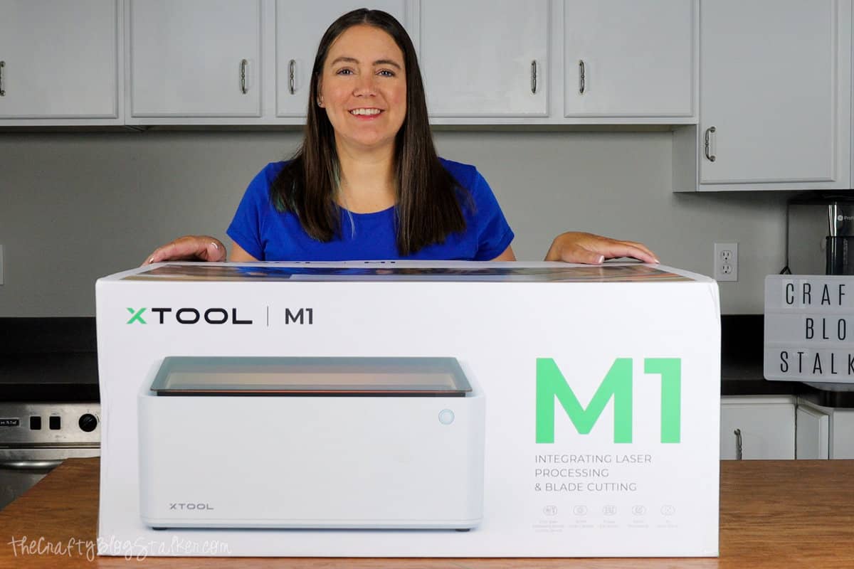a woman standing behind an xTool M1 branded box