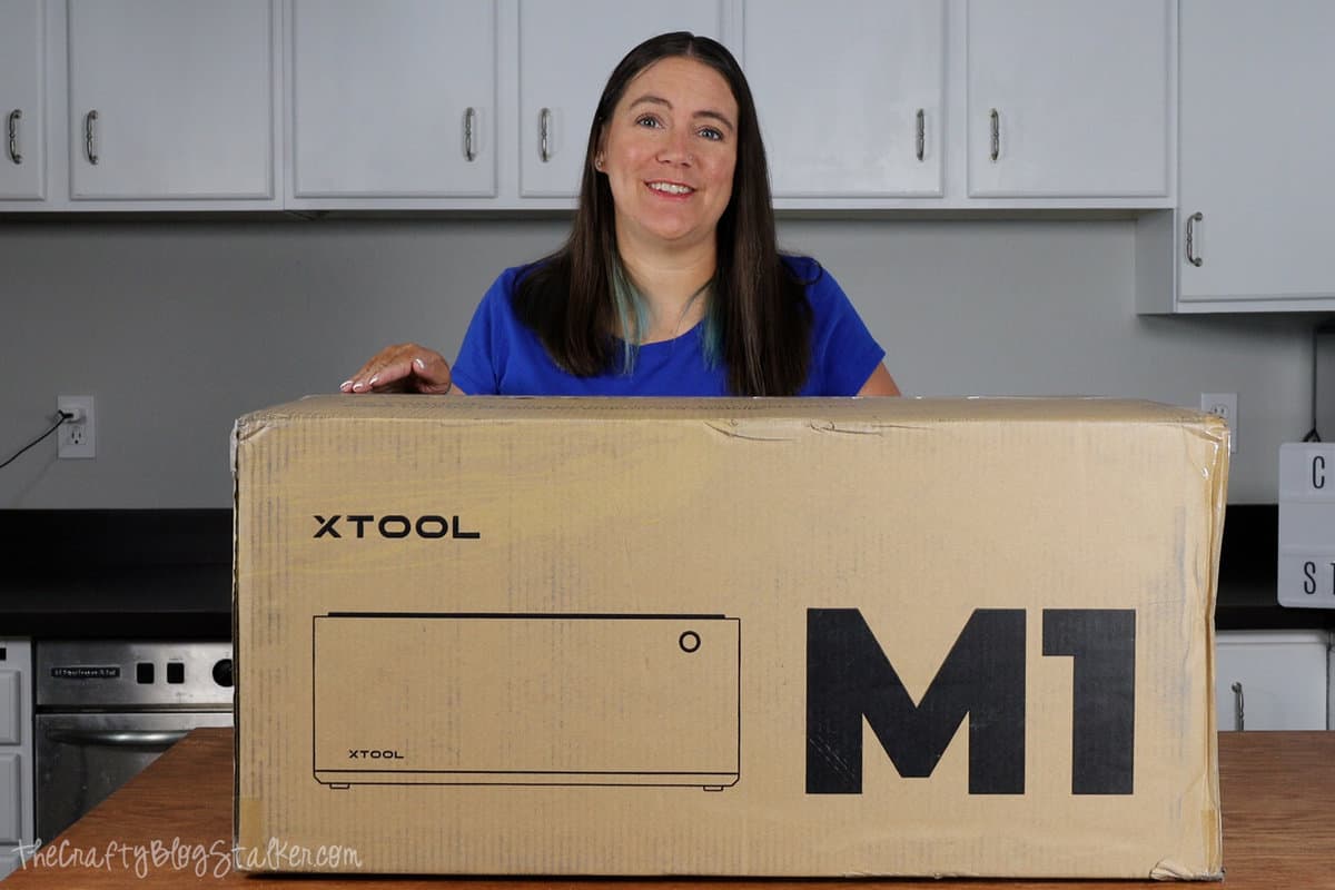 a woman standing behind an xTool M1 box 