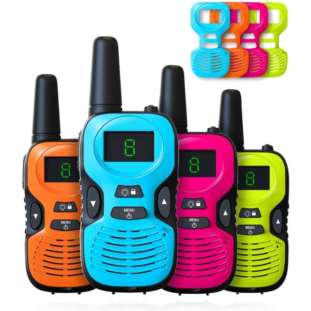 A set of four colorful kids' walkie talkies in blue, orange, pink, and green, each with a digital display and simple buttons, shown with matching belt clips.