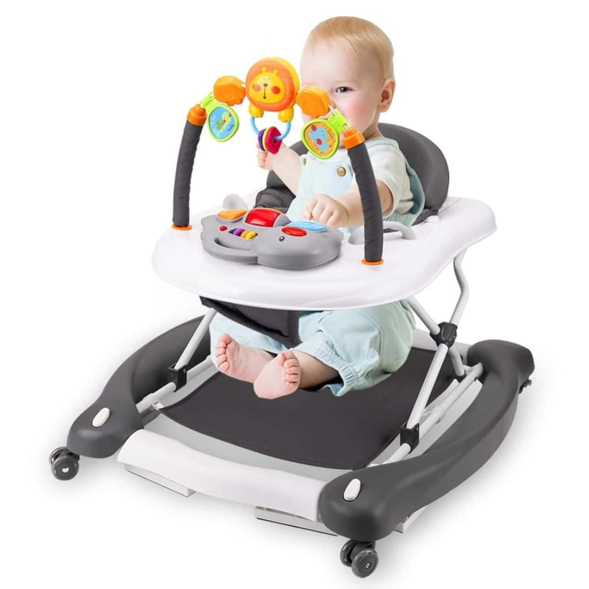 Infant seated in a baby walker with a white tray, colorful toys, and a padded seat, shown on a gray and white frame with small wheels.