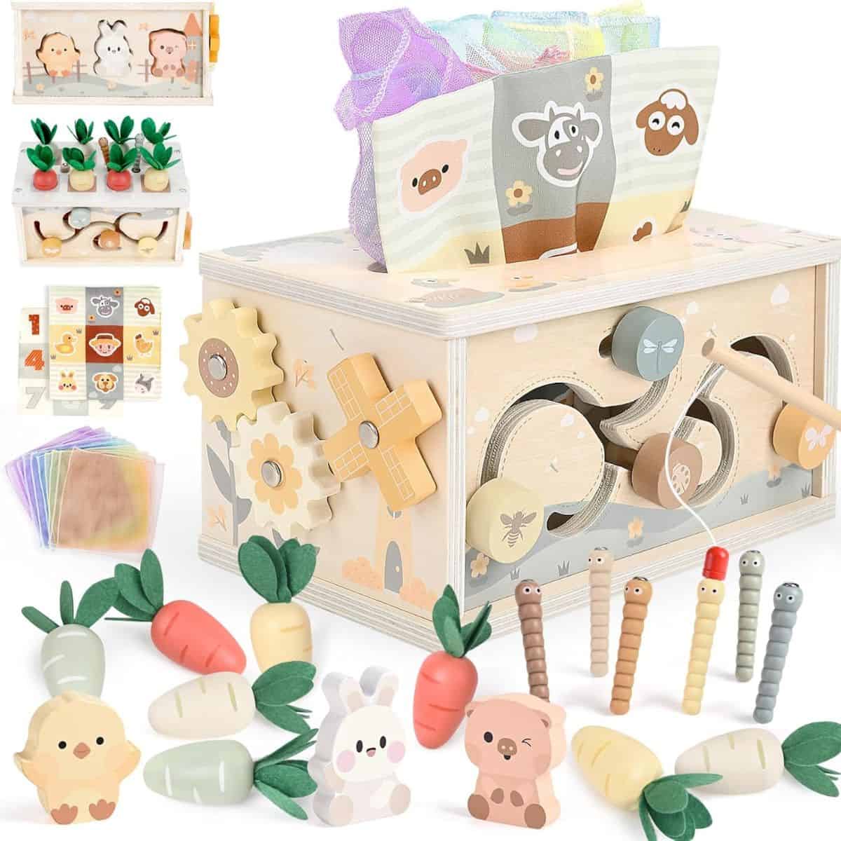 Wooden Montessori-style activity box with gears, pull toys, fabric tissues, carrots, worms, and cute animal figures arranged around it.