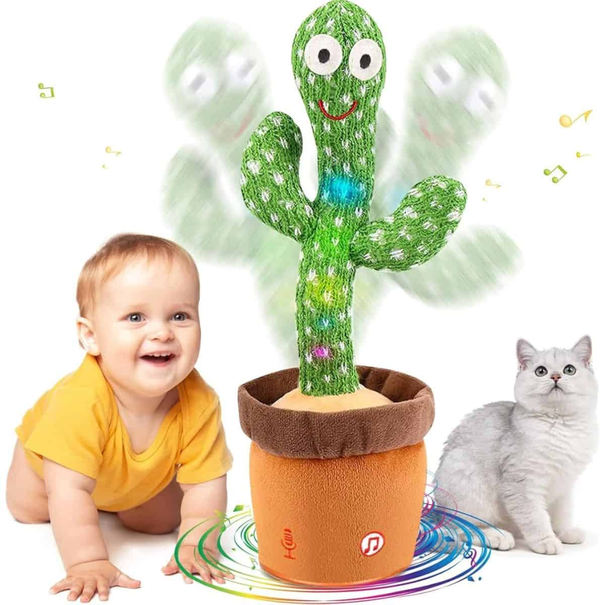 Baby and cat watching a plush dancing cactus toy in a fabric pot with colorful lights and musical notes around it.