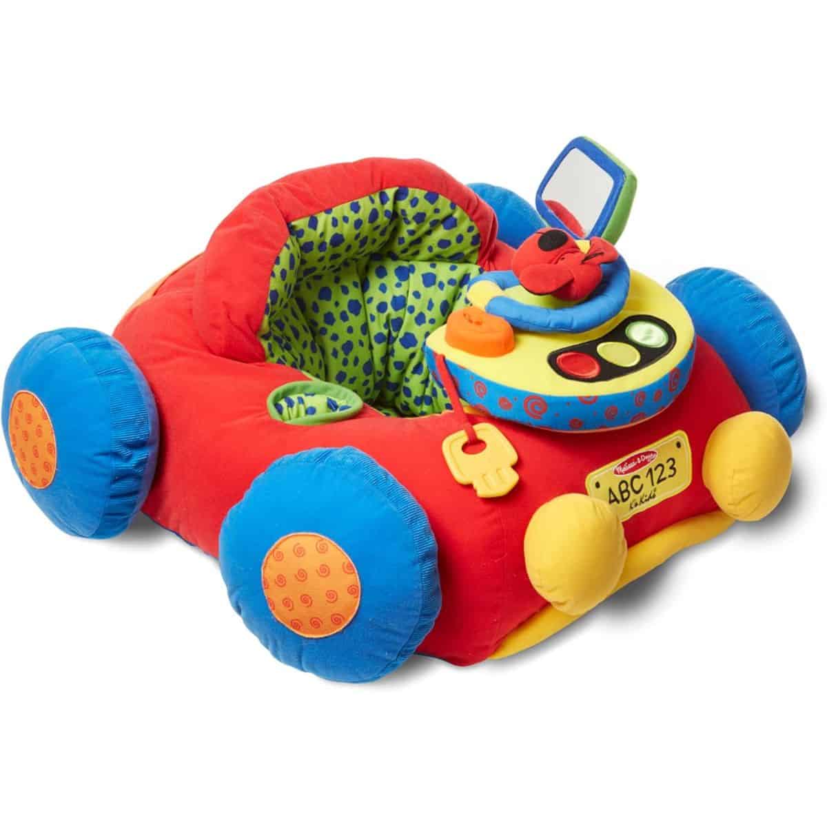 Colorful plush baby seat shaped like a car, featuring padded wheels, a soft steering wheel, toy dashboard, mirror, and attached key for sensory play.
