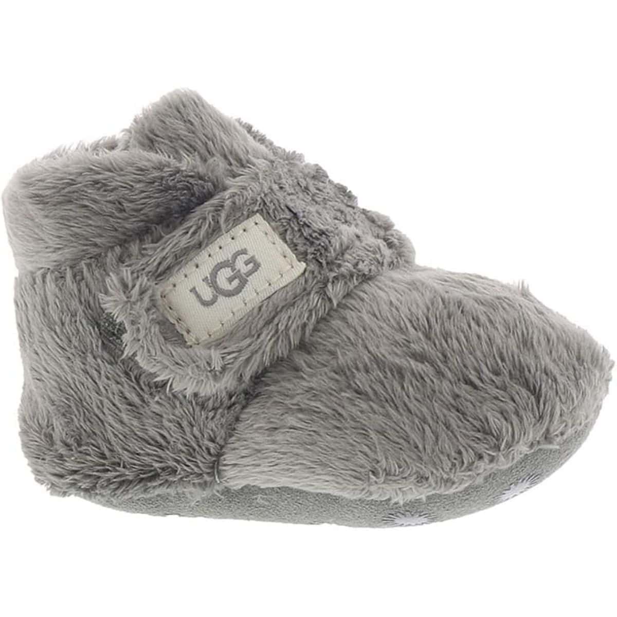 Gray fuzzy UGG baby boot with a soft sole and a small fabric tag on the side, shown in a close-up on a white background.