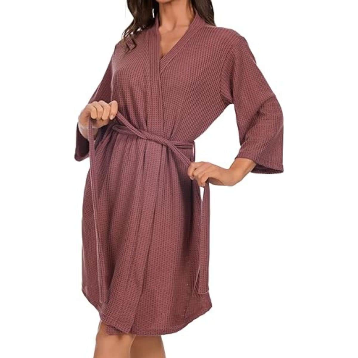 A woman wearing a knee-length waffle knit bathrobe with wide sleeves and a matching tie belt, shown in a relaxed fit for loungewear or spa use.