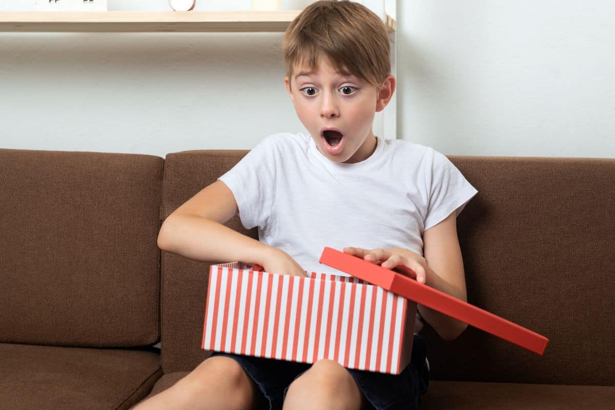 A child opening a gift with an excited look on his face.