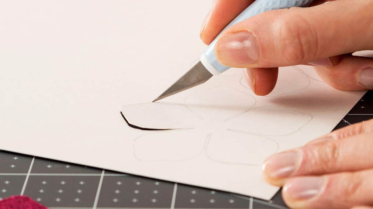 Hands using a Cricut TrueControl knife to cut a flower shape.