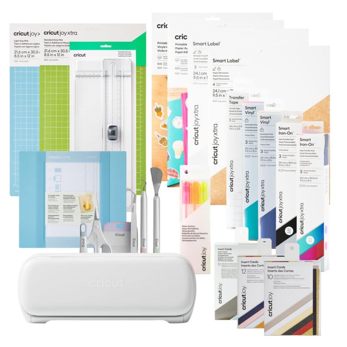 A Cricut Joy Xtra machine displayed with cutting mats, Smart Vinyl, Smart Iron-On, Smart Label sheets, tools, markers, transfer tape, and insert cards.