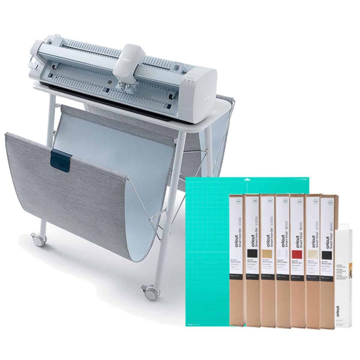A Cricut Venture cutting machine on its stand shown with a large cutting mat and multiple rolls of Smart Vinyl and Smart Media supplies.