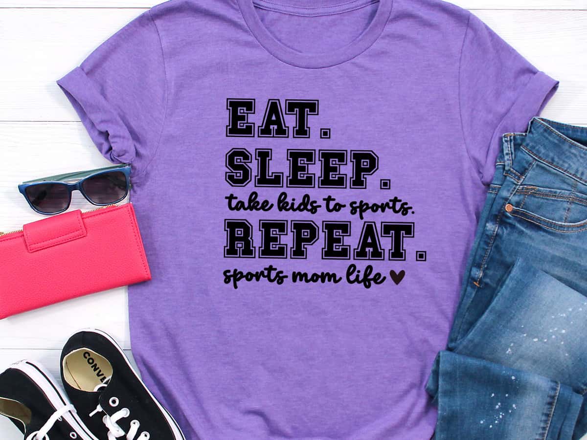 A T-shirt with a design that reads eat sleep take kids to sports repeat sports mom life.