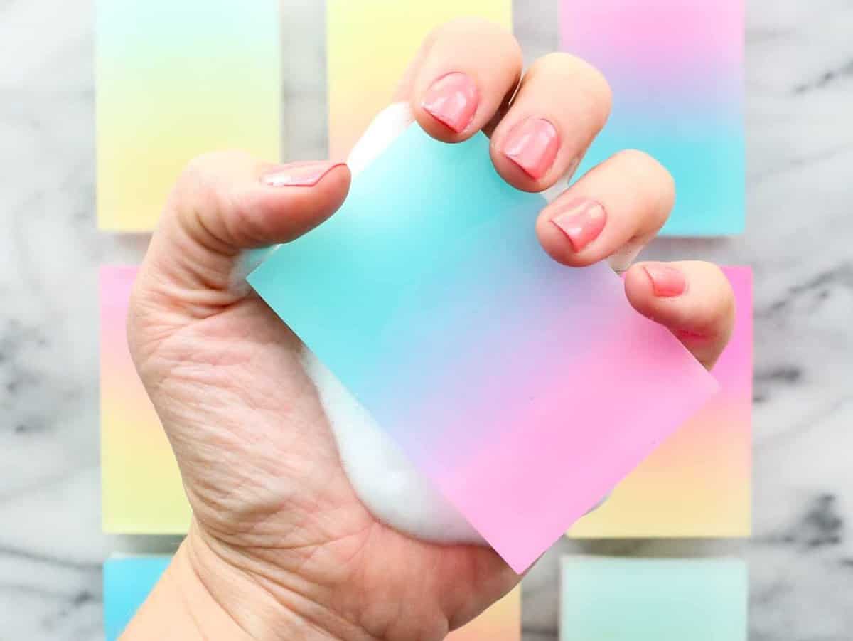 A gradient soap bar held in a hand showing fingernails.