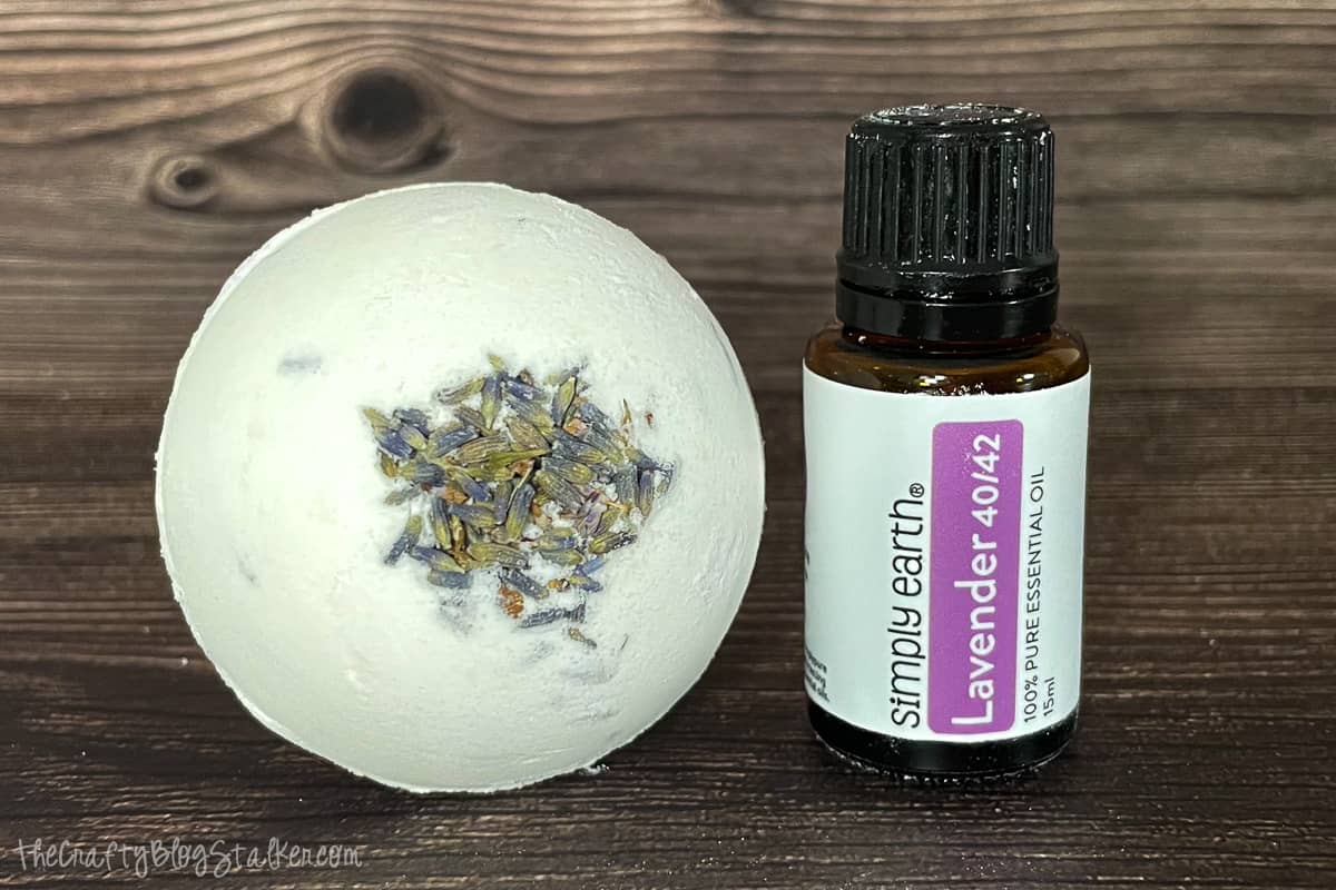 Lavender bath bomb with a bottle of Simply Earth Lavender Essential Oil.
