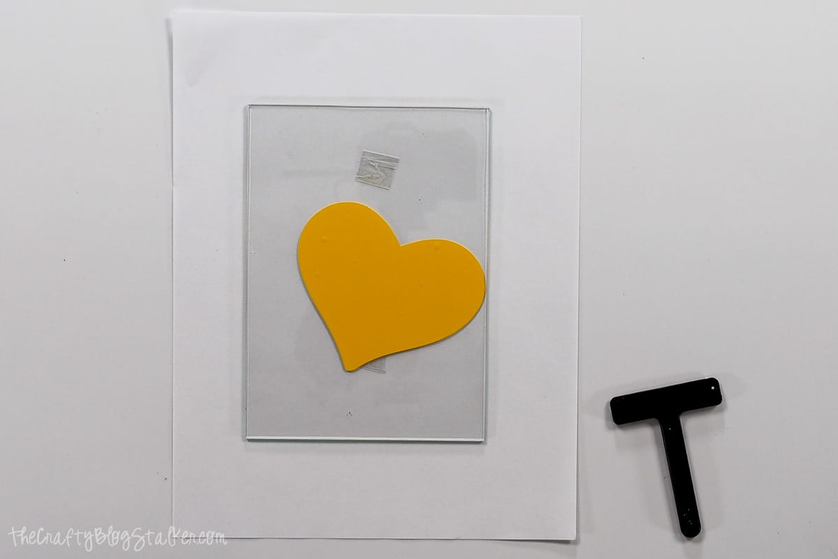 A sheet of glass with a vinyl heart on it.