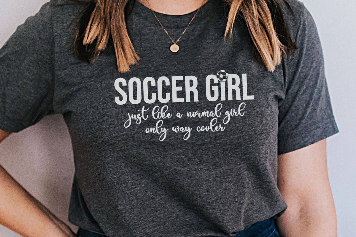 Woman wearing a shirt with a design that reads 'soccer girl just like a regular girl only way cooler'.