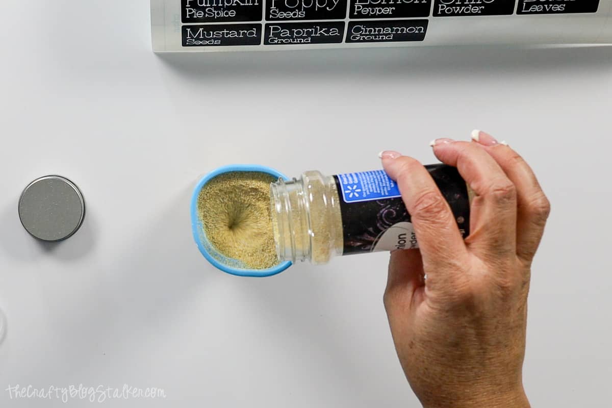 Pouring Onion Powder into a new spice container.