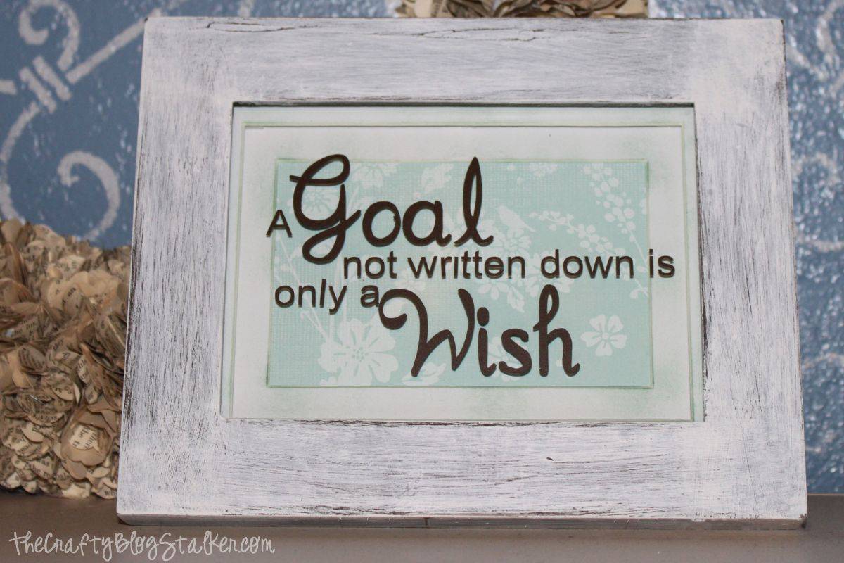 A distressed frame on a shelf with the quote "A goal not written down is only a wish".