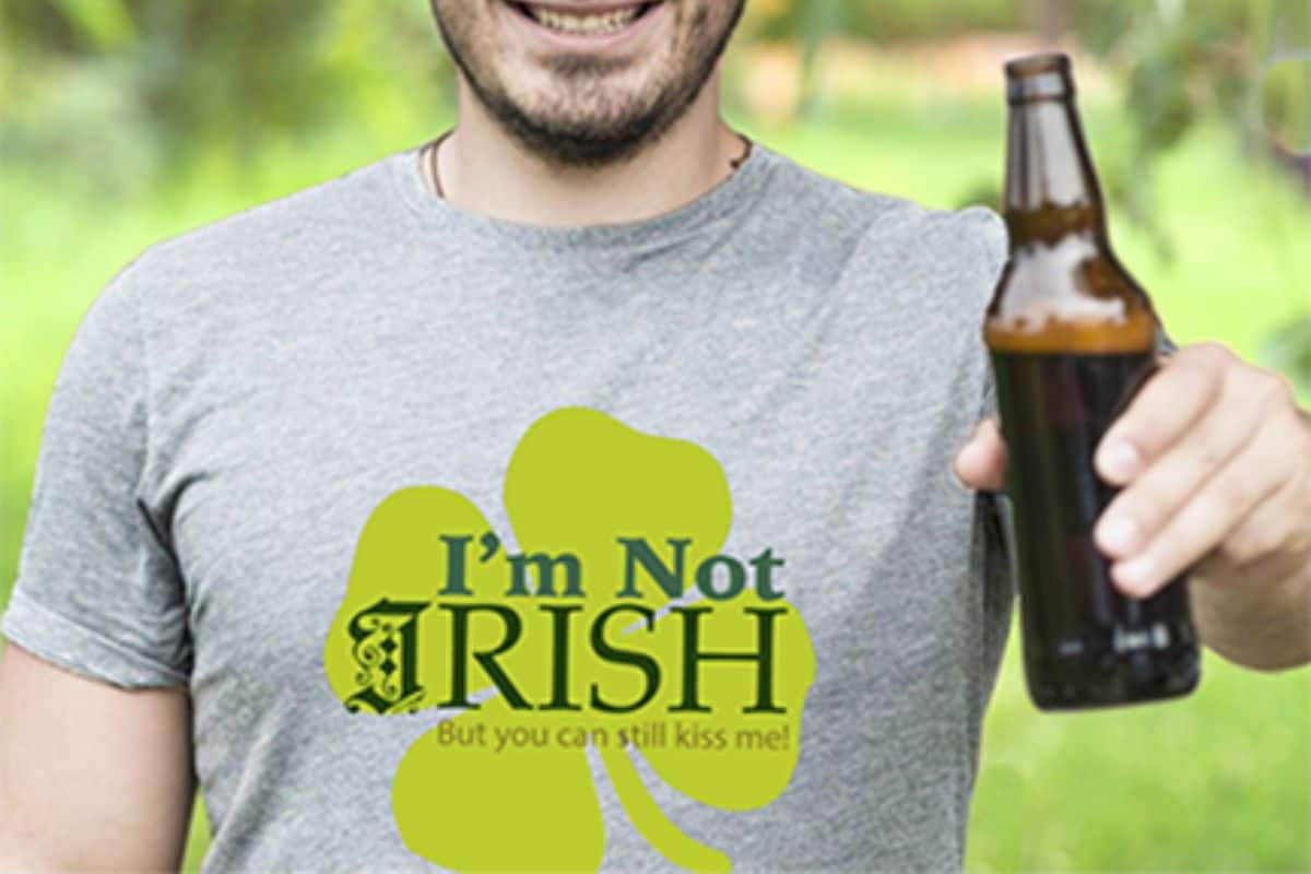 A man wearing a gray shirt with a design that reads I'm not Irish but you can still kiss me.