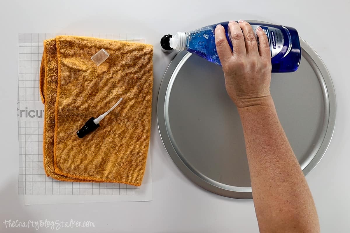Adding a drop of dish soap to a small spray bottle.
