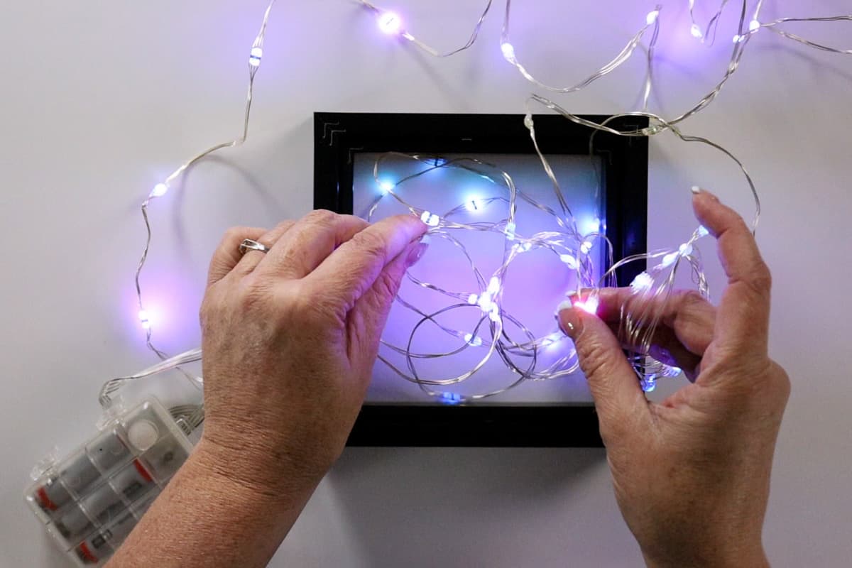 Stretching out the string of lights and placing them in the frame.