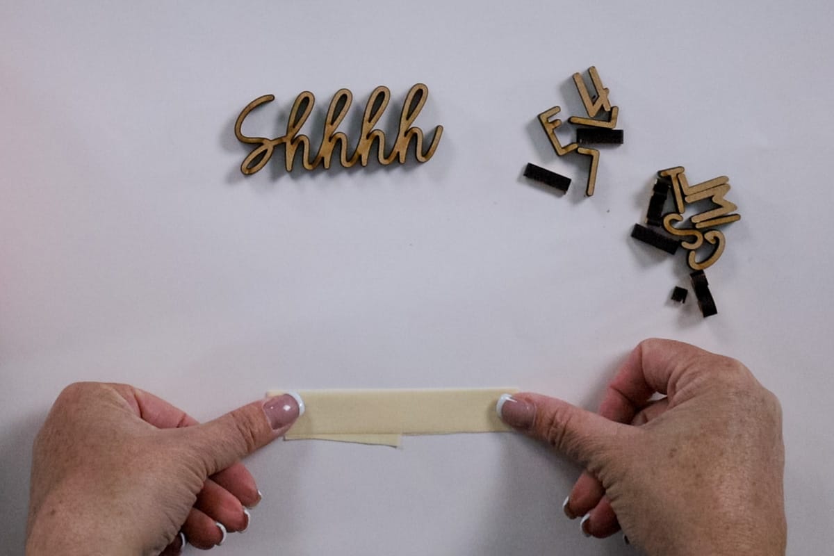 A loop of masking tape placed on a sheet of paper to hold the letters.