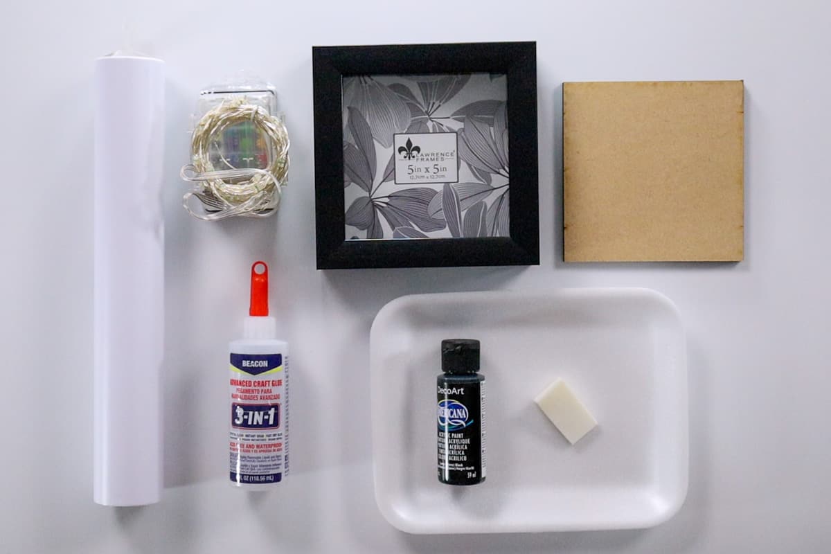 Supplies needed including white vinyl, fairy lights, shadow box frame, mdf, black paint and glue.