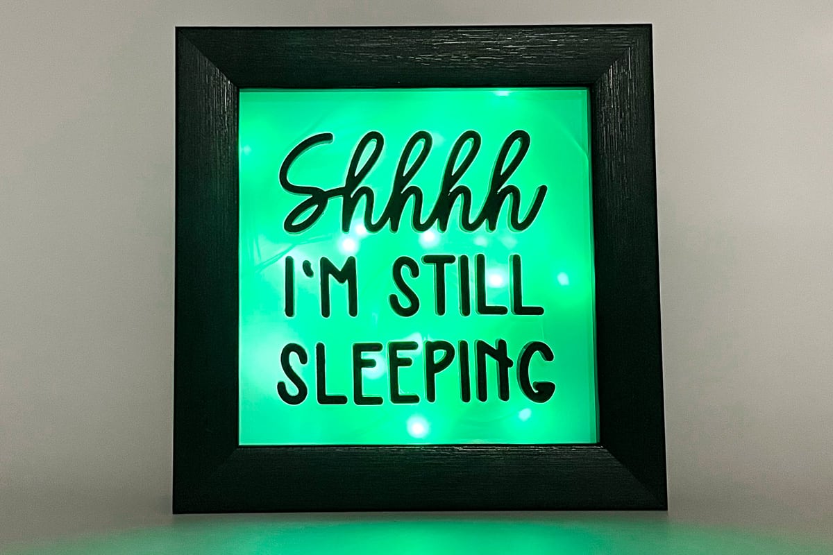 A DIY night light that is glowing green with the words "Shhhh I'm still sleeping".