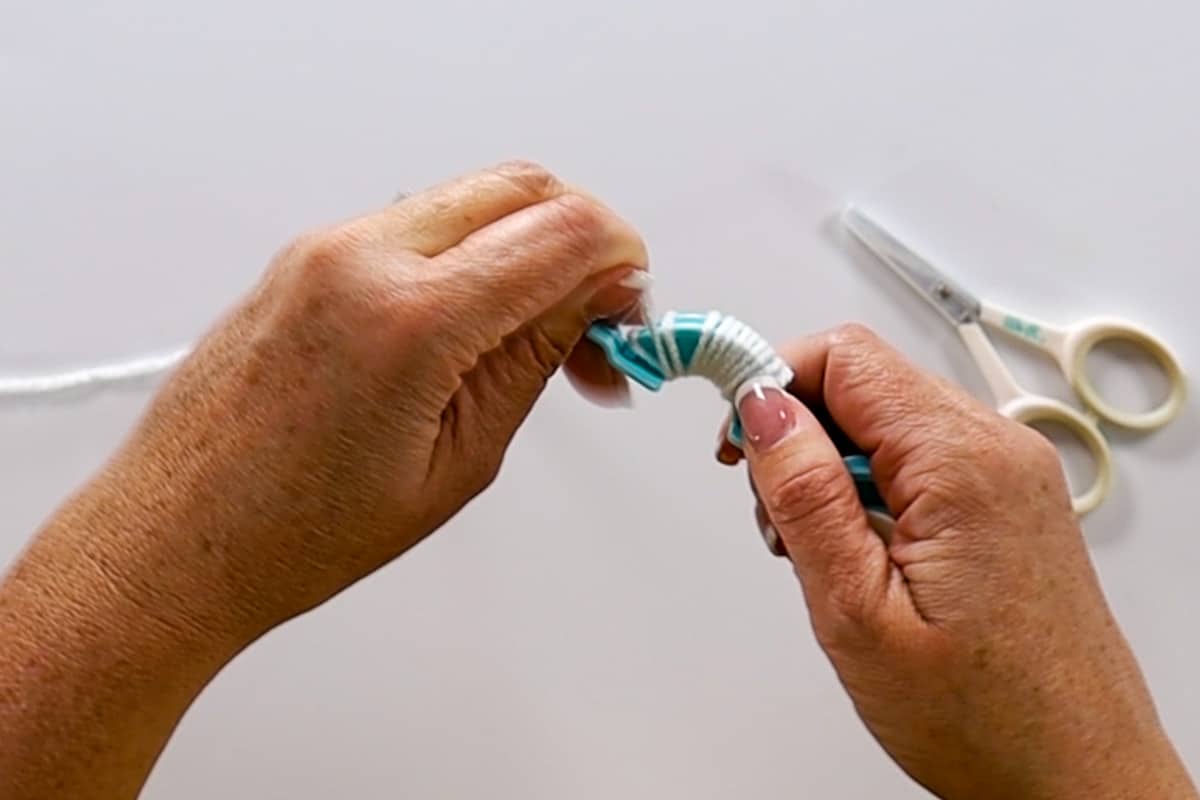 Wrapping a pom pom maker with white yarn.