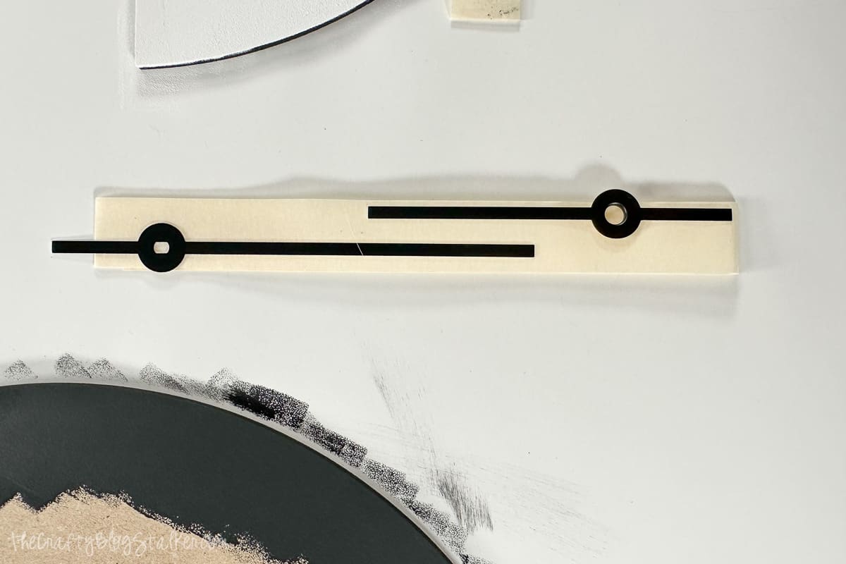 Clock hands adhered to masking tape to hold in place.