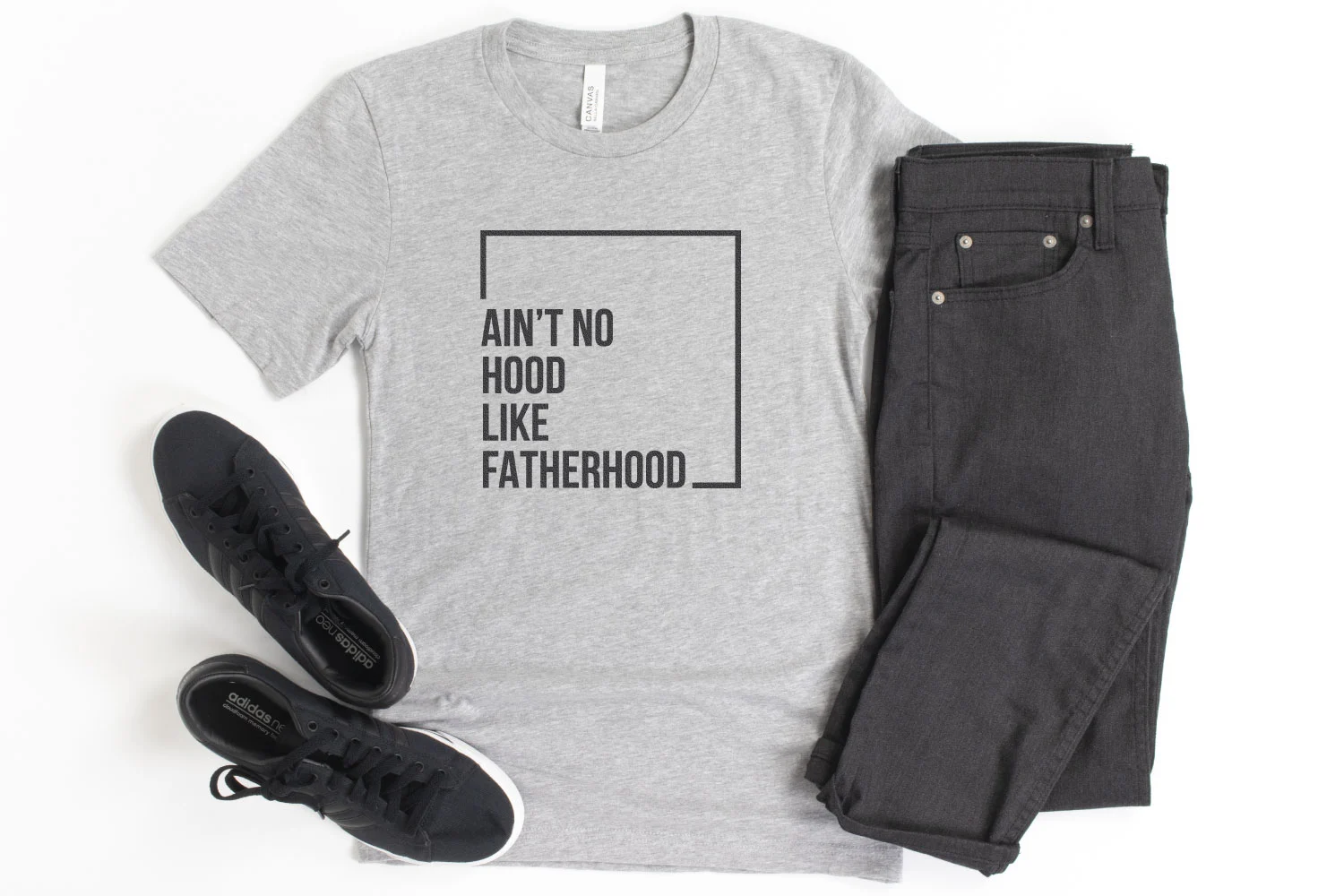 Flat lay with a gray t-shirt and a design that reads "ain't no hood like a fatherhood".