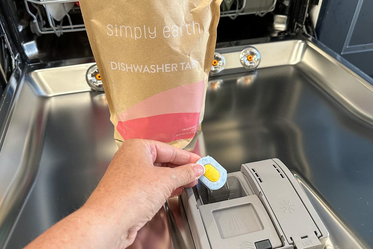 Placing a dishwasher tab into the soap dispenser in a dishwasher.