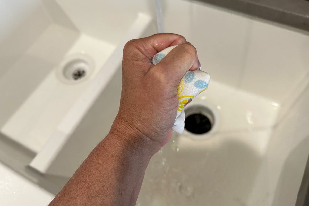 A hand squeezing the water out of a Swedish Dishcloth.