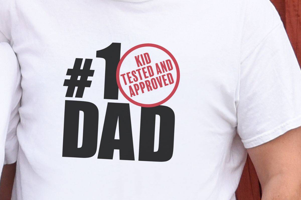 A man wearing a shirt with a design that reads " Number One Dad Kid Tested and Approved".