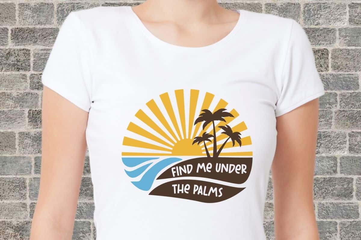 Woman wearing a white t-shirt with a layered design that reads find me under the palms.