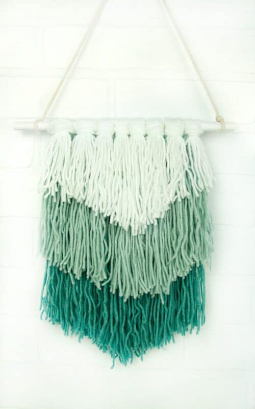 A layered woven wall hanging in three different shades of green.