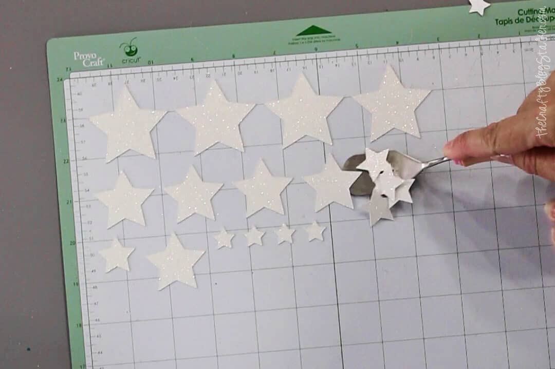 Removing paper glitters stars from a Cricut mat using the spatula tool.