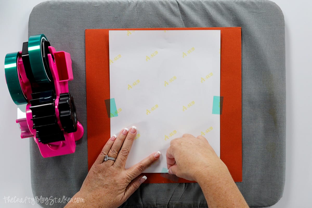 Taping the sublimation print onto the puzzle blank.