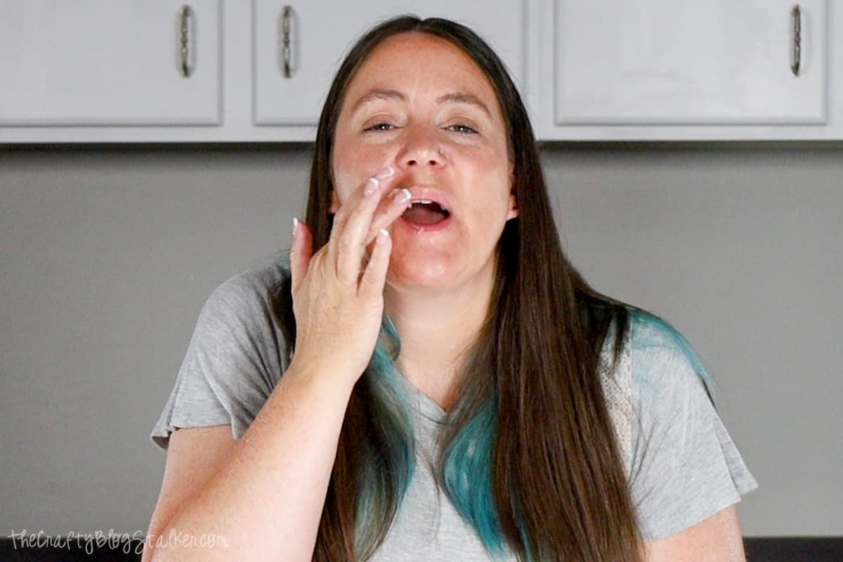 A woman rubbing homemade lip scrub onto her lips.