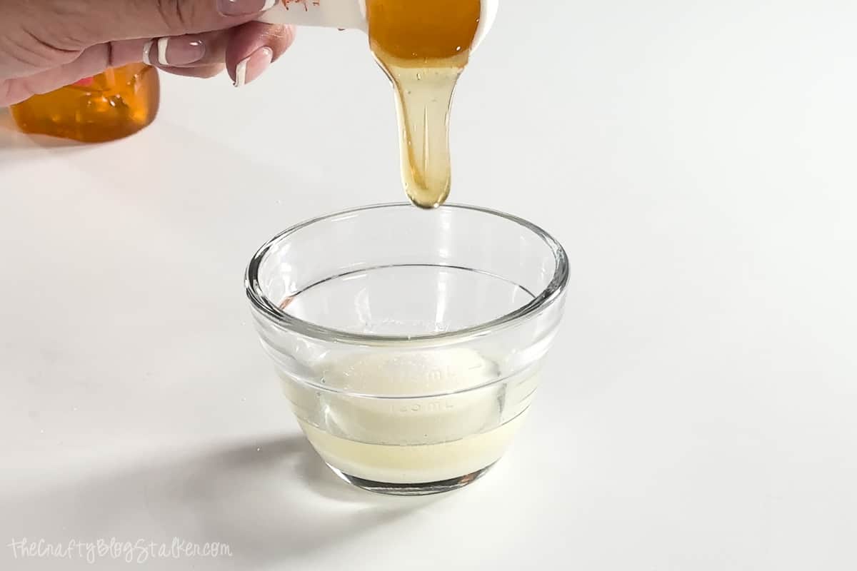 Pouring honey into a small mixing bowl.