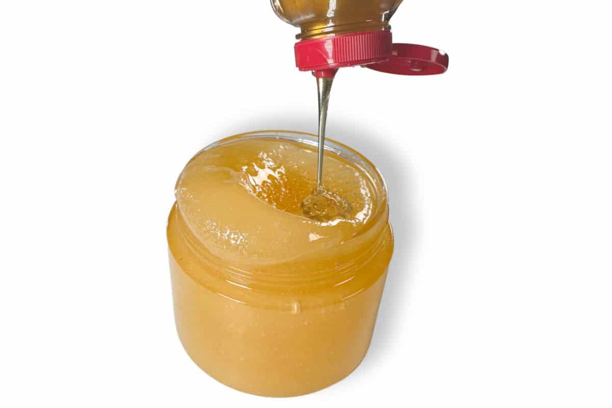 Grapefruit and honey home remedy lip scrup, with honey being poured directly into the container.