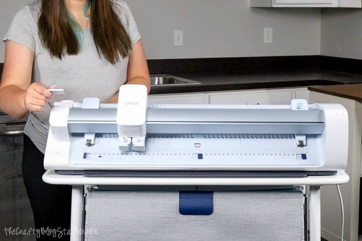 A woman lifting the lever on the Cricut Venture.